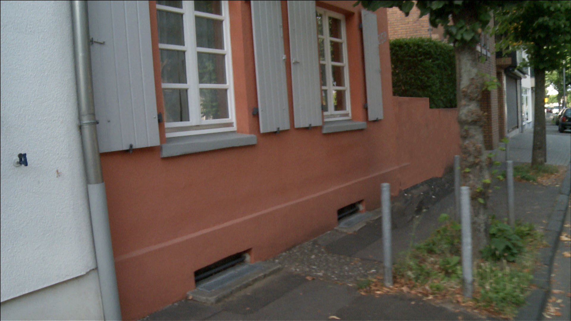 Ein Bürgersteig vor einer roten Hausfassade.
